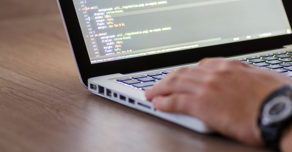 Person coding on a laptop with HTML code on screen, showcasing development work.